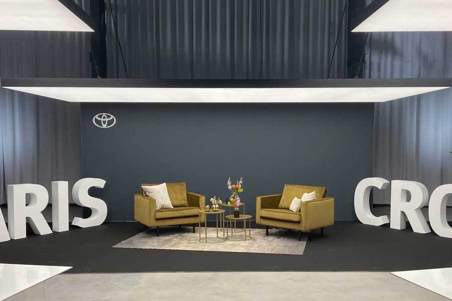 Team Standbouw conferentie stand met moderne lounge-opstelling, stijlvolle verlichting en opvallende 3D-letters | professionele standbouw voor zakelijke events en internationale beurzen
