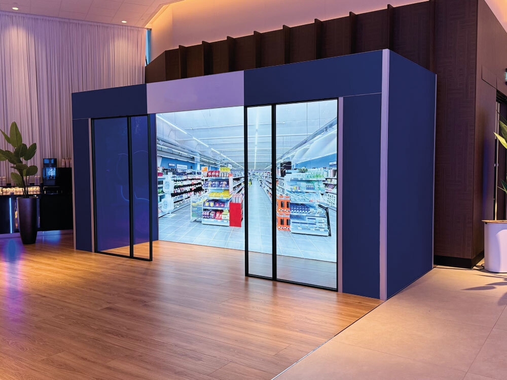 Innovatieve winkelpui met Lightbox en glasframes die schuifdeuren lijken, duurzaam en modulair gebouwd door Team Standbouw voor een Nederlandse prijsvechter.